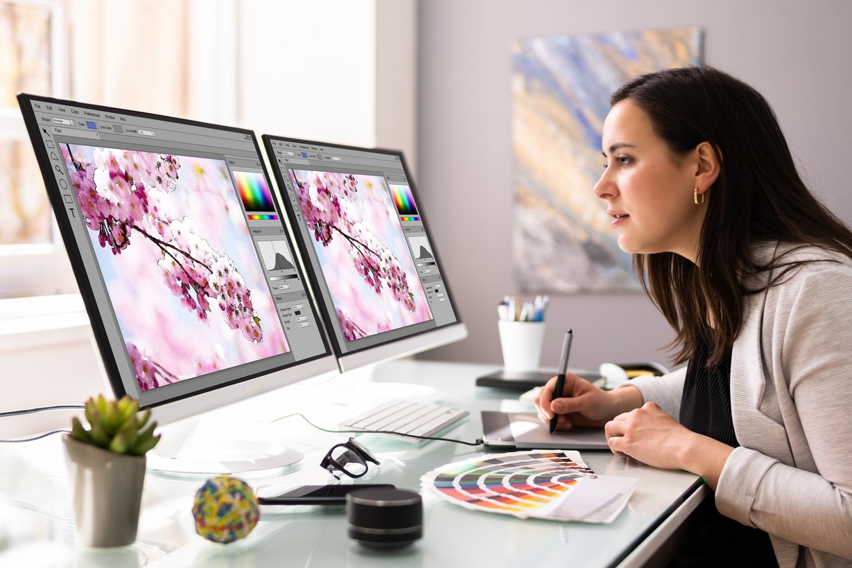 a graphic designer sitting at a desk in front of a computer looking at a design