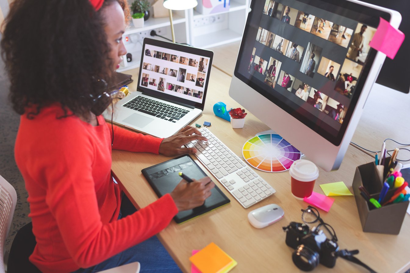 a grahic designer working on a resume for a client working on a laptop and a computer